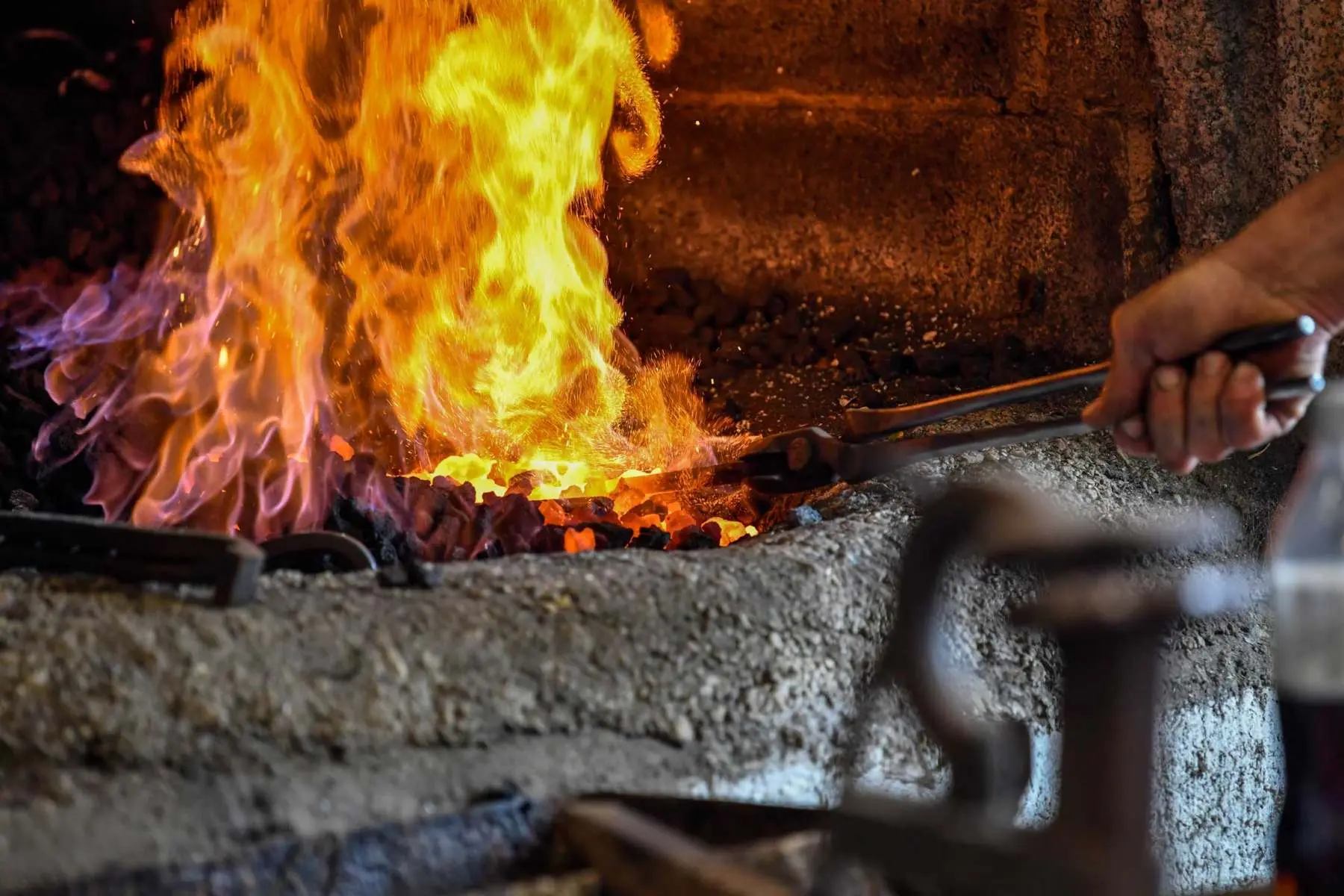 Farrier working at the forge fire, Hook Norton Farriers, Swerford, Oxfordshire