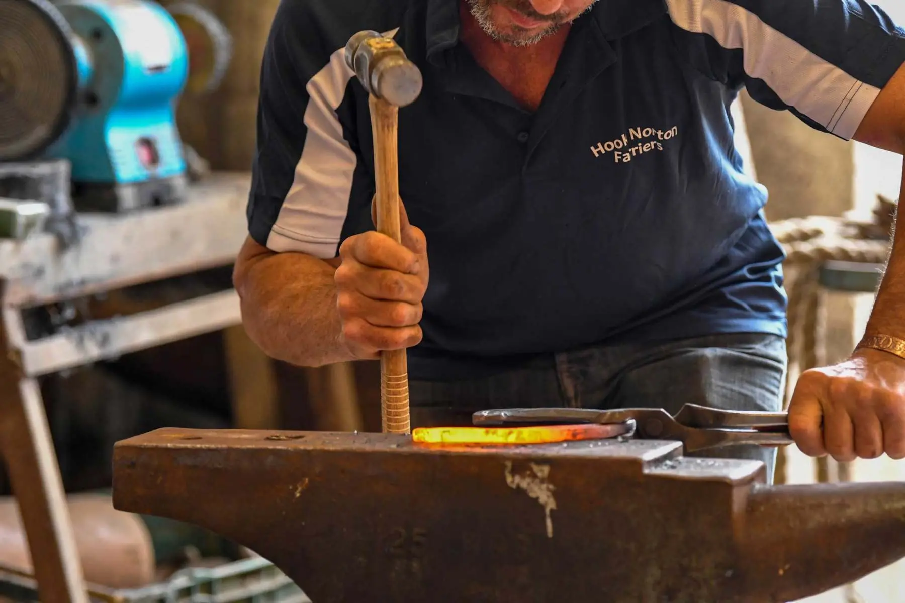 Shaping a horseshoe at the anvil, Hook Norton Farriers, Swerford