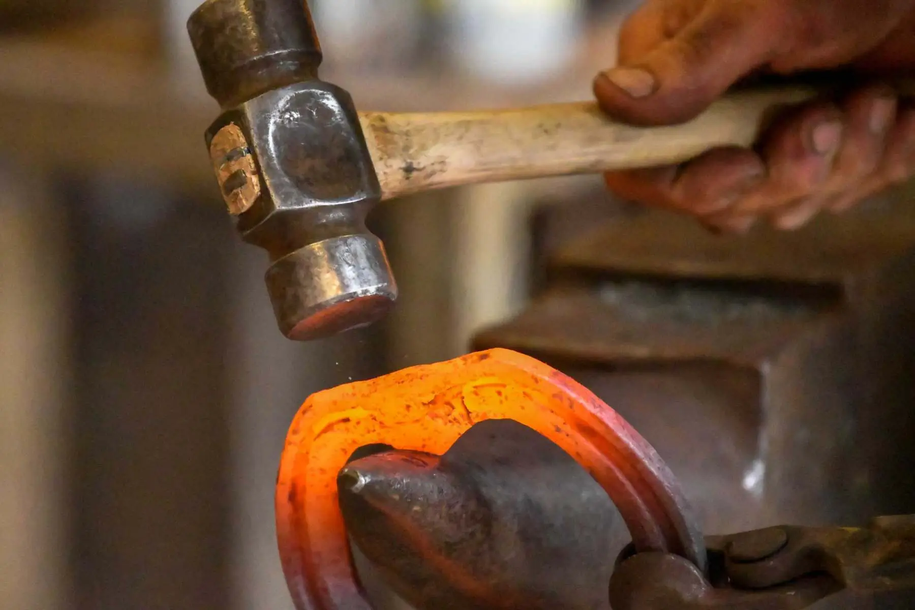 Farrier forging a red hot horseshoe on the anvil, Hook Norton Farriers, Chipping Norton